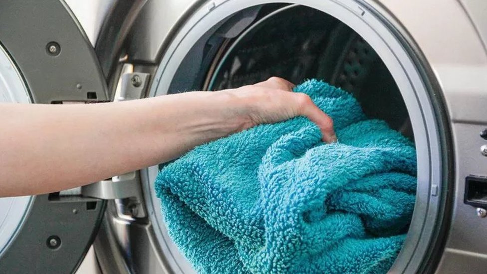 Serviette de bain roul&eacute;e pos&eacute;e sur du linge