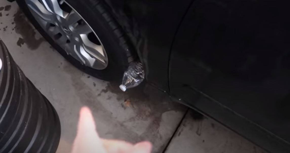 Femme regardant avec méfiance une bouteille près de sa voiture