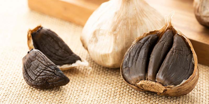 Gousses d'ail noir bio sur fond naturel