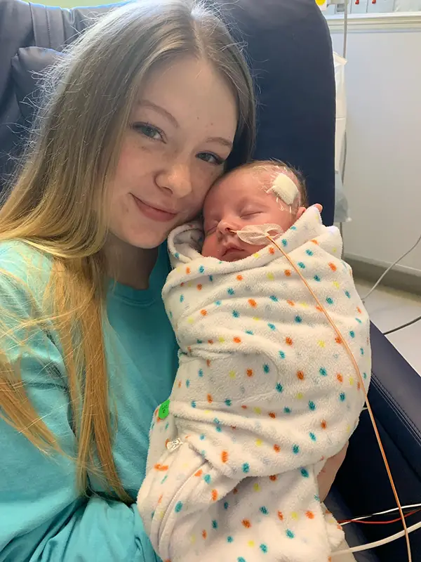 Nouveau-n&eacute; Karson dans les bras d'un parent, entour&eacute; d'amour