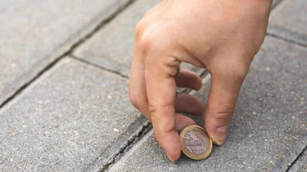 Personne ramassant une pièce de monnaie par terre