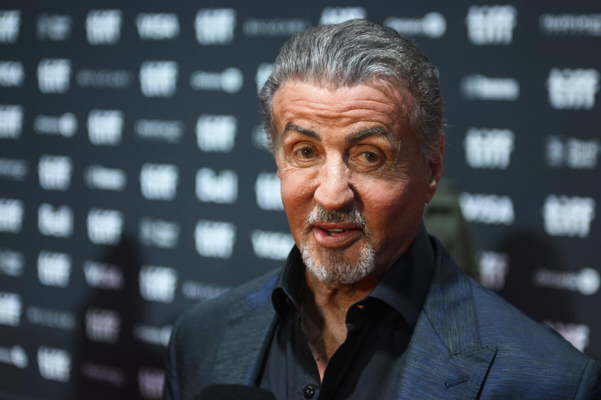 Stallone souriant, bras croisés