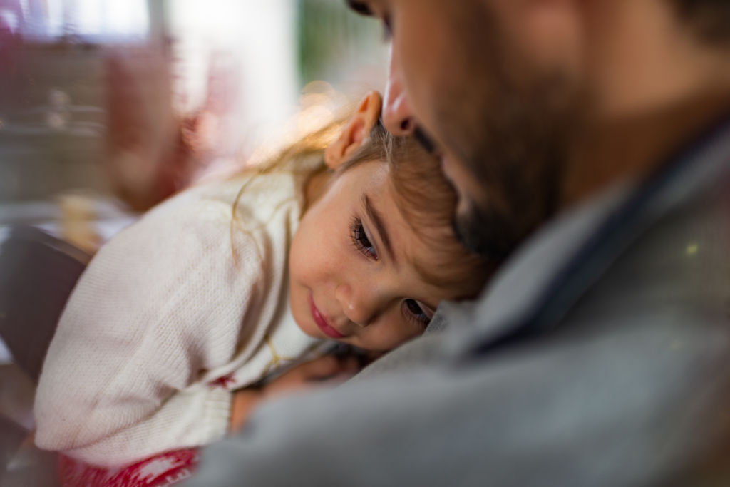 Un p&egrave;re et sa fille partageant un moment complice devant un sapin de No&euml;l