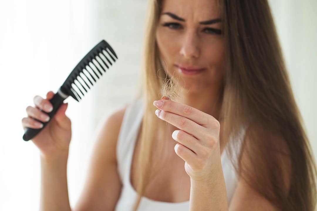 Femme regardant avec inquiétude les cheveux restés sur son peigne