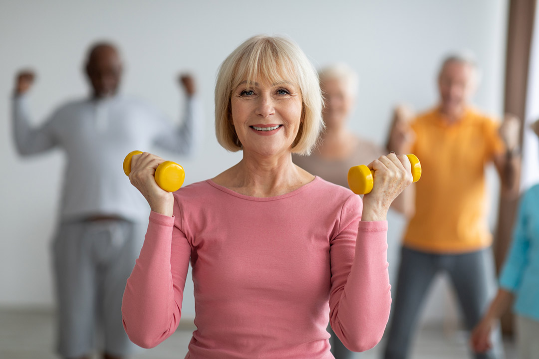 Femme d'âge mûr souriante effectuant des exercices de gymnastique douce en extérieur