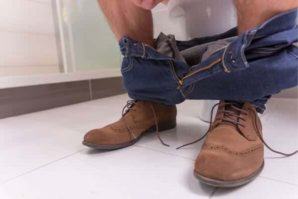 Homme assis aux toilettes