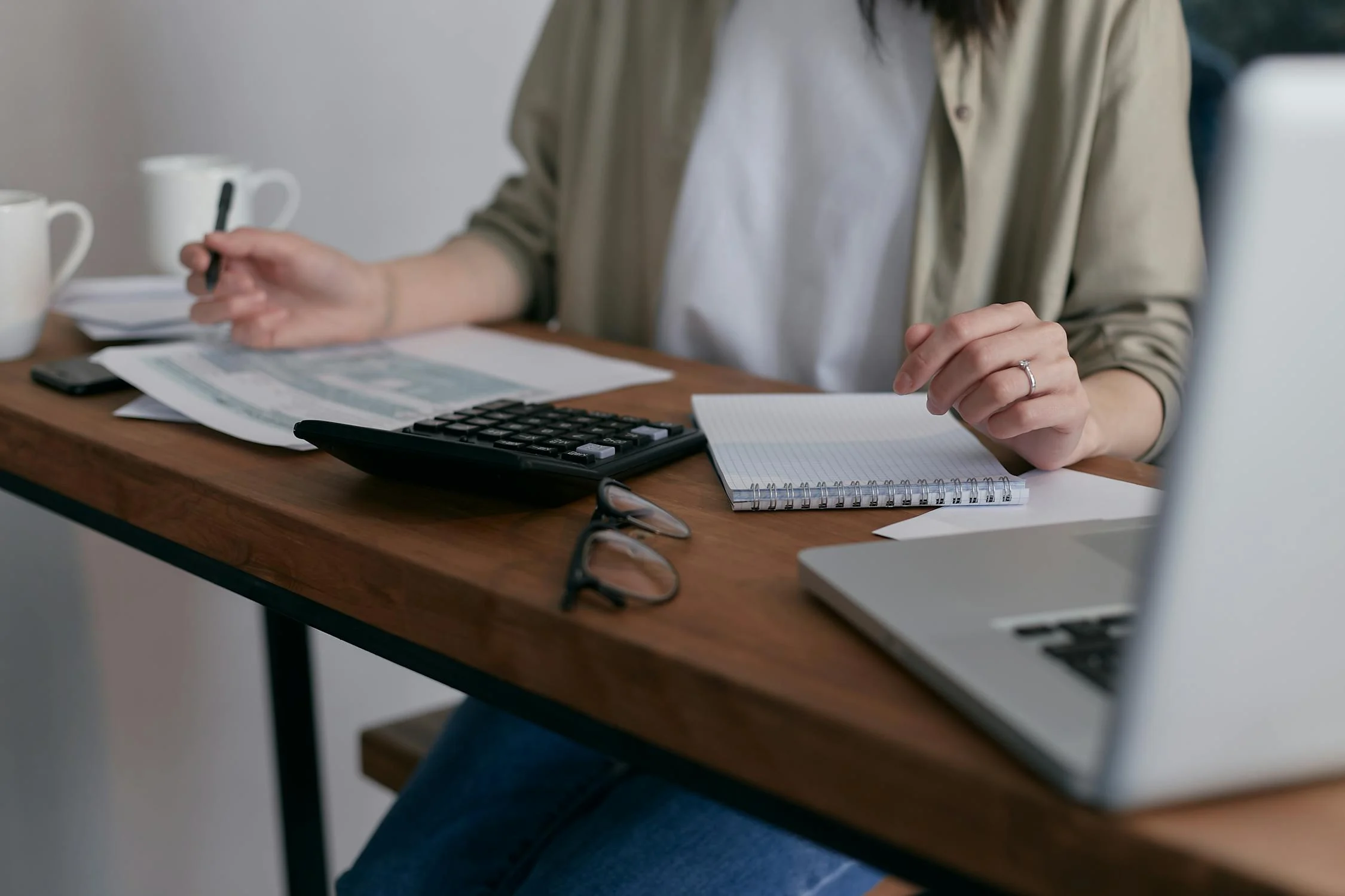 Femme travaillant sur ordinateur portable, assise à un bureau, les jambes croisées