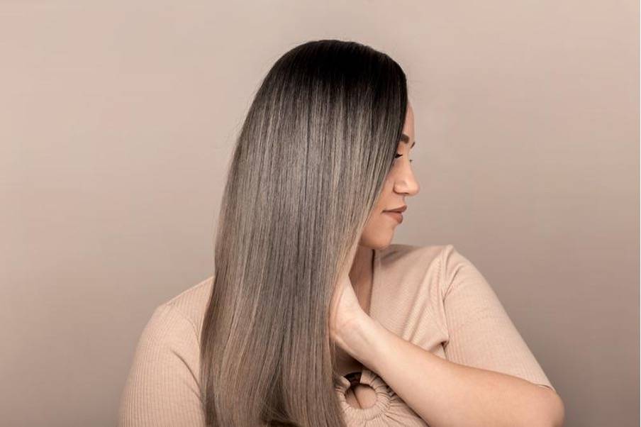 Femme aux cheveux longs et lisses, souriante, tenant une feuille verte