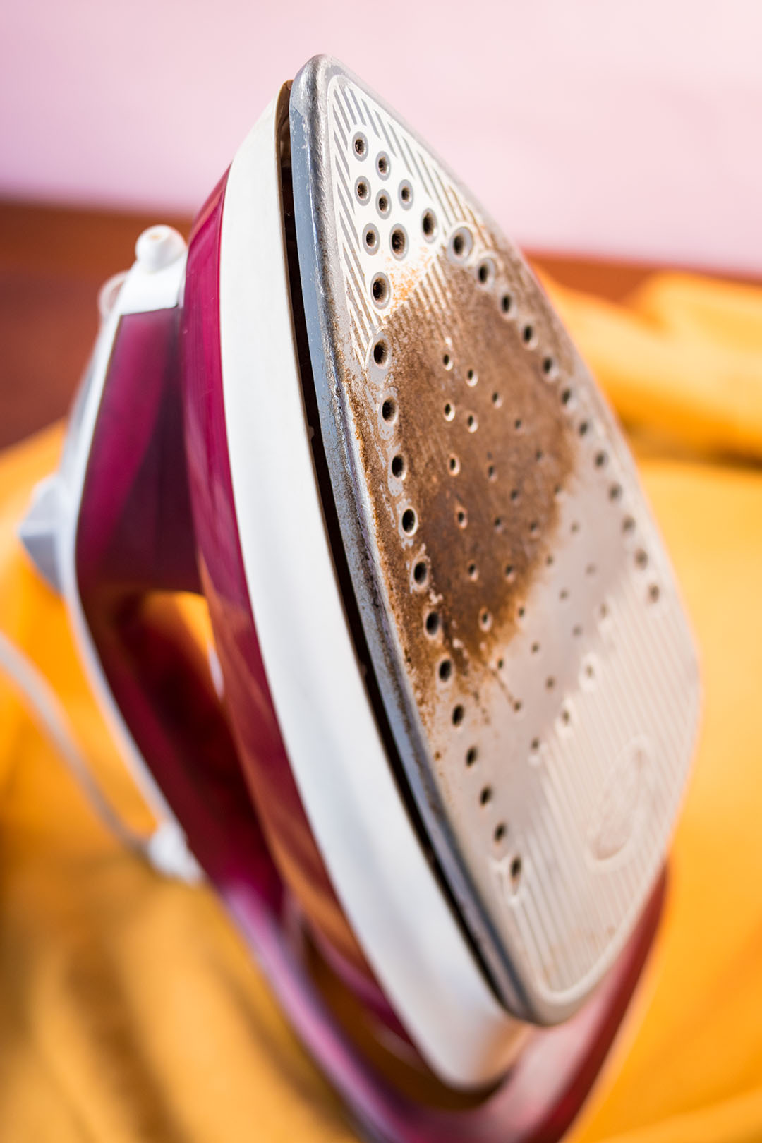 Fer &agrave; vapeur pos&eacute; sur une planche &agrave; repasser avec un chiffon jaune